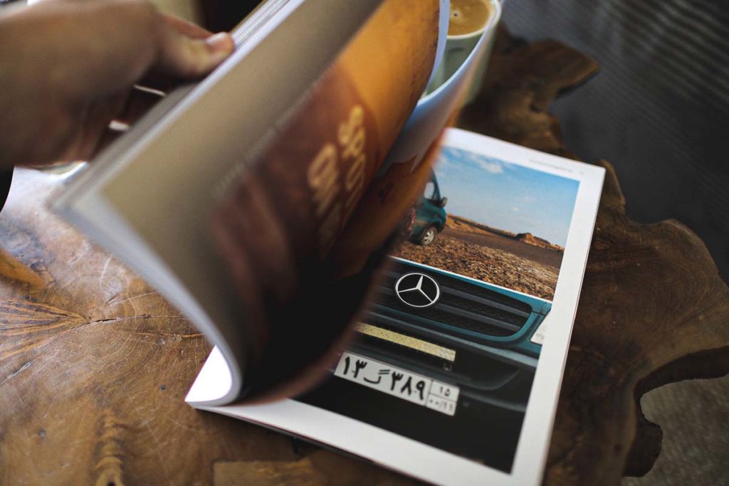 Hands flicking through pages of Advanture Magazine, showcasing printed photography and slow journalism.